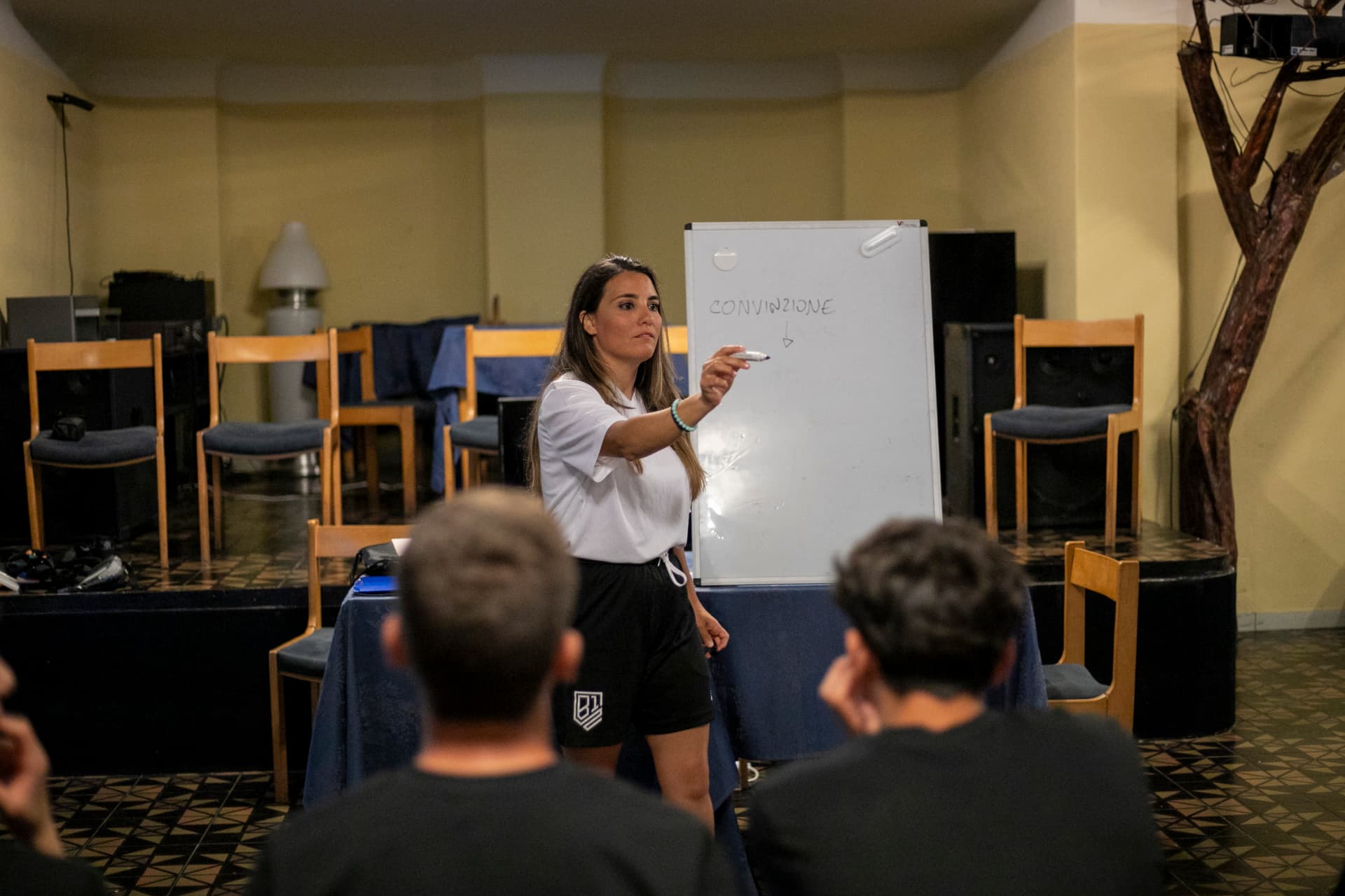 Alice Fatuzzo durante una sessione di formazione con una squadra, davanti a una lavagna con la parola convinzione
